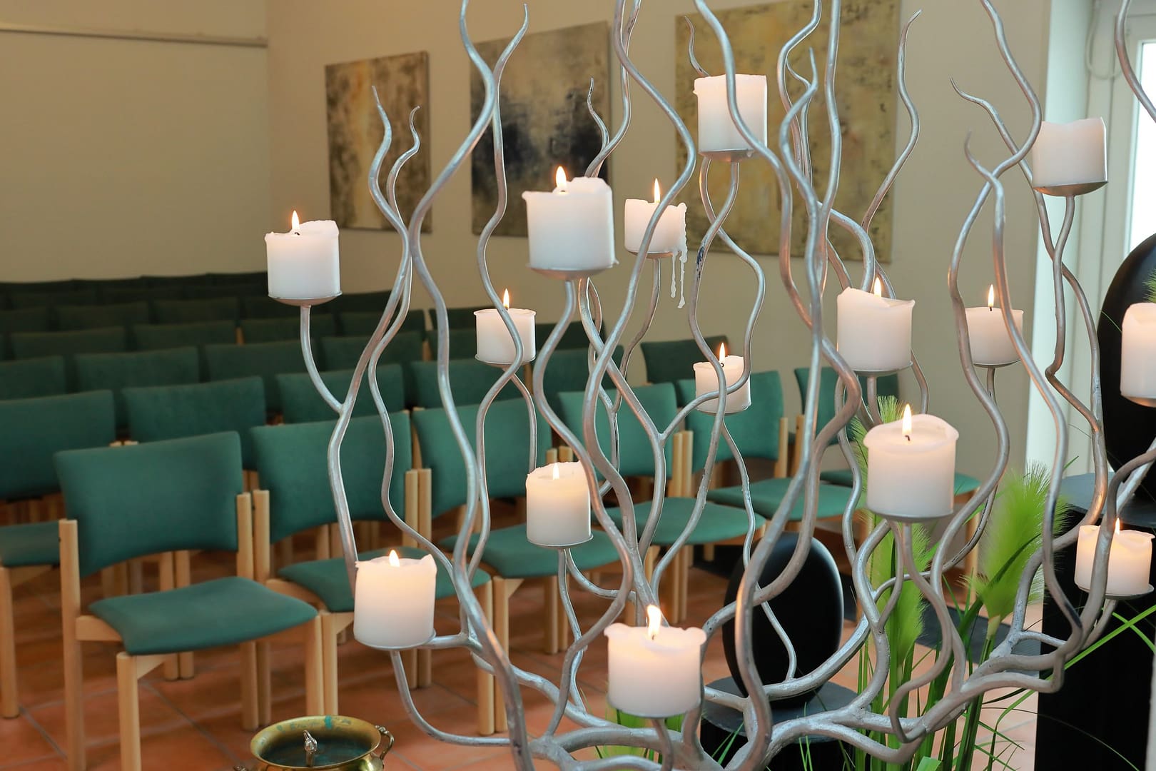 Kerzenbaum mit brennenden Kerzen vor den Stuhlreihen der Trauerhalle